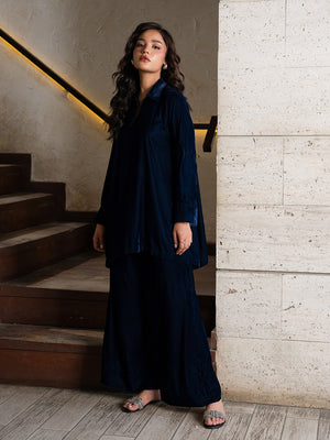 Woman in a navy blue outfit standing on a staircase with a neutral wall background
